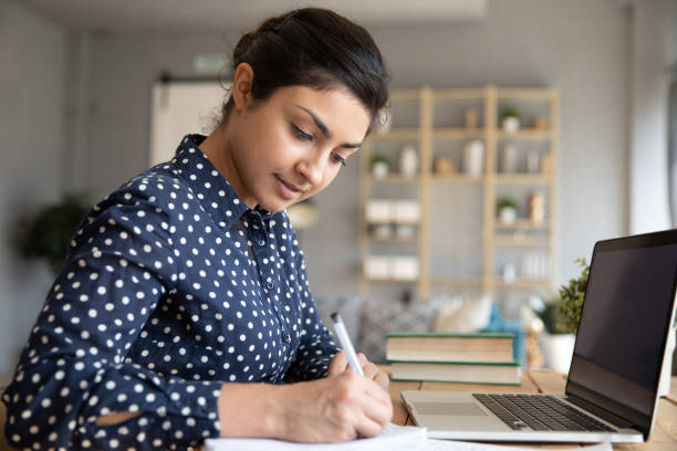 istock Smart Indian girl make notes studying on laptop at home 1208855989