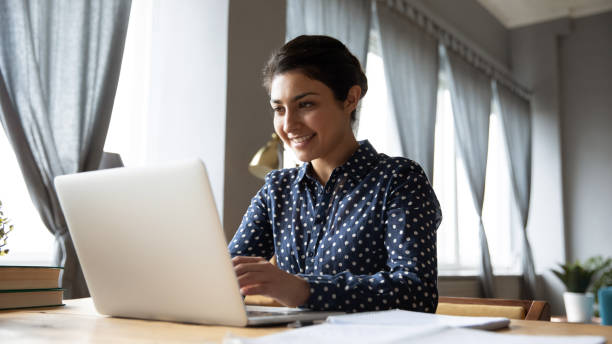 feliz jovem indiana ocupada trabalhando em laptop - medical research healthy lifestyle paper healthcare and medicine - fotografias e filmes do acervo