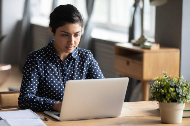 istock Focused Indian girl studying on laptop at home 1208856018