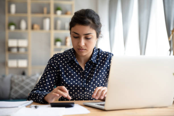 istock Focused ethnic woman paying bills online on laptop 1208856037