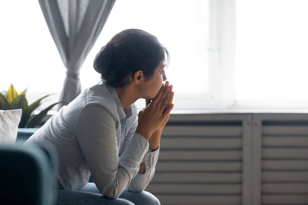 Pensive indian girl lost in thoughts suffering from depression Pensive millennial Indian girl sit on couch at home look in distance thinking pondering, thoughtful young ethnic woman lost in thoughts feel stressed suffer from depression or emotional breakdown one young woman only stock pictures, royalty-free photos & images