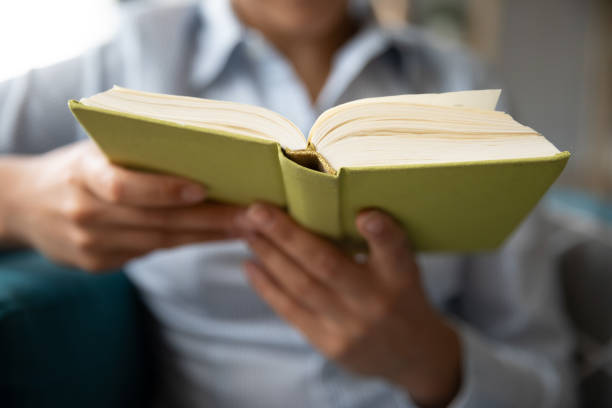 istock Young woman sit on couch reading book 1208856068