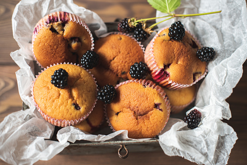 Homemade muffins with blackberry berries on a brown wooden background
