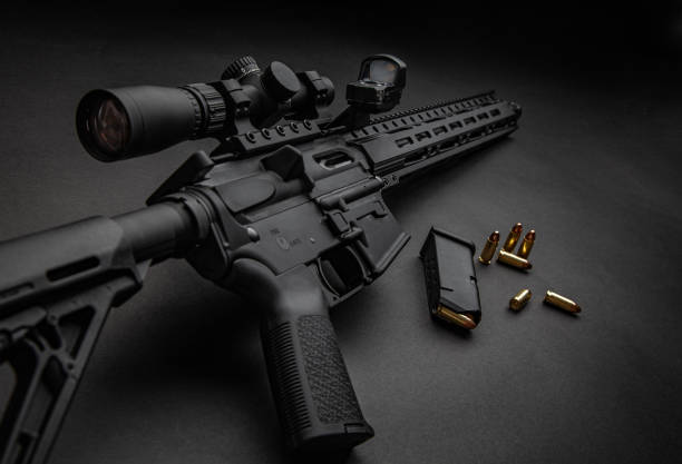 Modern automatic carbine with optical and collimator sight. A rifle with two sights on a dark background. Cartridges for weapons near a carbine.