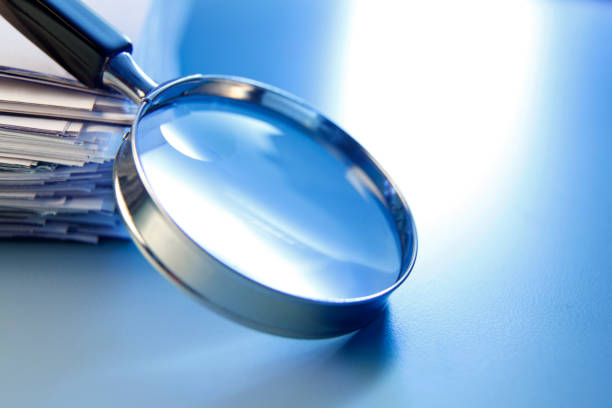 istock Magnifying Glass Leaning Against Stack Of Papers 1208860317