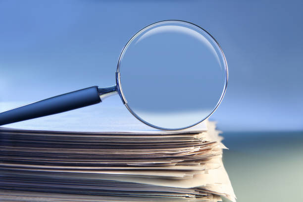 istock Magnifying Glass Sitting On Top Of Stack Of Papers 1208860376