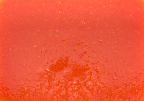 Photo of The texture of the tomato juice with the pulp in a rectangular shape. Red is a warm tone with a barely orange tinge.