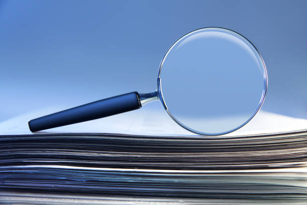 istock Magnifying Glass Sitting On Top Of Stack Of Papers 1208862774