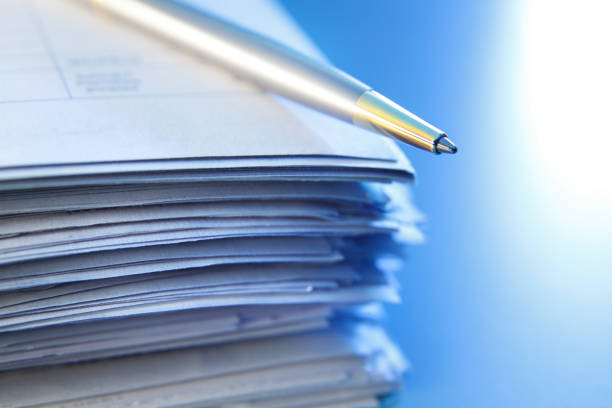 Ballpoint Pen On Top Of Stack Of Paperwork A close up of a ballpoint pen resting on top of a stack of paper documents. Photographed with a vey shallow depth of field. legal document stock pictures, royalty-free photos & images