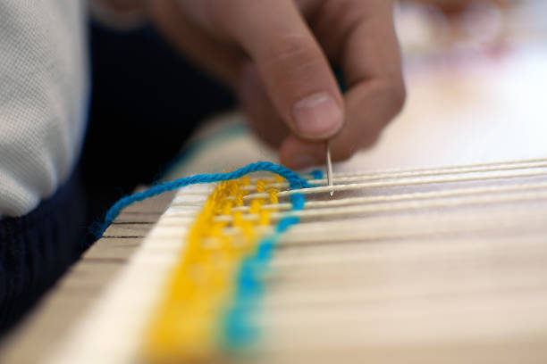 Little children hands weaving loom in art theraphy class at school. Education concept. Telar weave looom