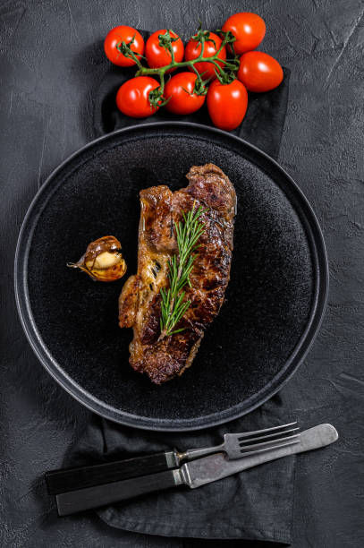 istock Beef strip loin steak on black background.  Marble premium beef 1208865167