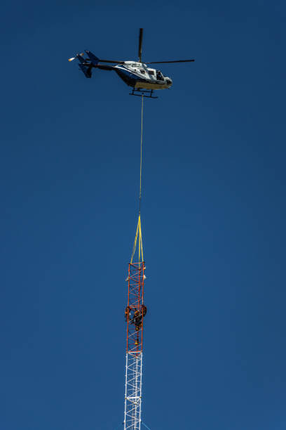 Helicopter aligning component onto radio mast stock photo