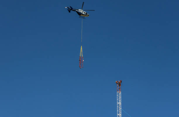 Helicopter approaching tower with next component stock photo