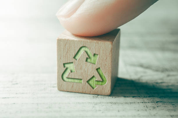 ícone de reciclagem verde em um bloco de madeira em uma mesa, tocado por um dedo - recycling recycling symbol environmentalist people - fotografias e filmes do acervo