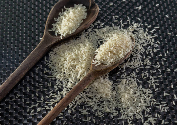 istock Peeled and processed grain rice on a dark background 1208877152