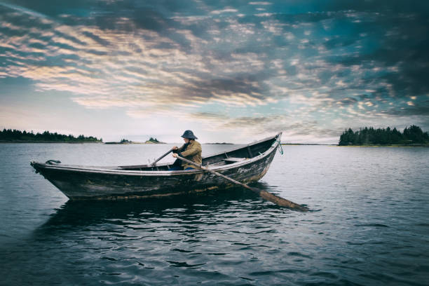 Old Man and the Sea A mature man rowing a boat into the open rough sea. rowing boat stock pictures, royalty-free photos & images