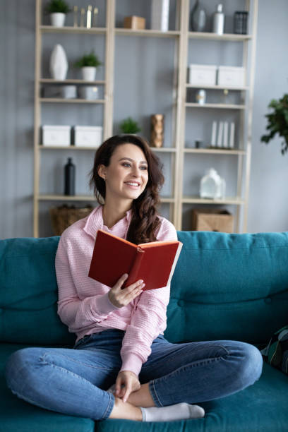 istock Young beautiful girl cozy on a sofa reading a book. 1208878152