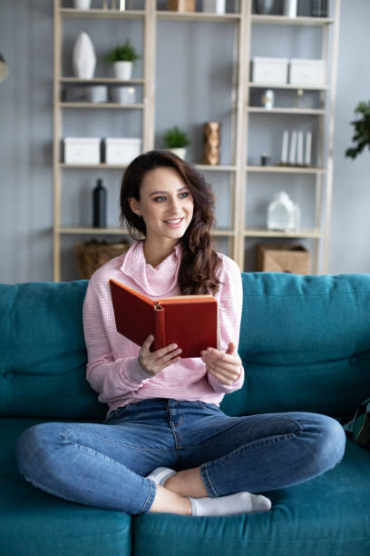 istock Young beautiful girl cozy on a sofa reading a book. 1208878343