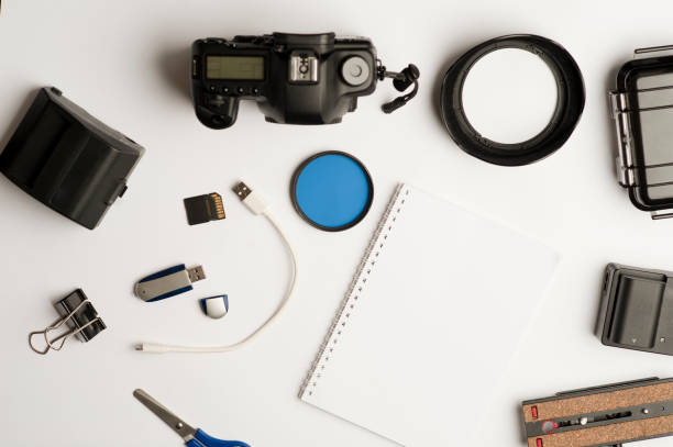 istock Flat assembly composition with photographic production equipment, with writing book, and accessories, on plain white background, top view 1208881030