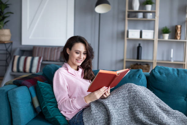 istock Happy young woman relaxing reading sit on sofa at home. 1208883534