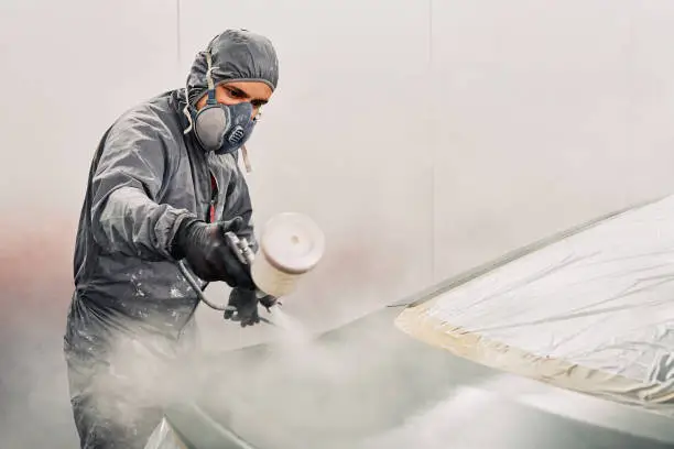 Photo of A man painting a car