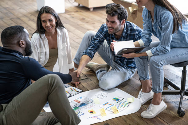 istock Sharing opinions. Group of confident business people discussing something while looking at blueprint laying on the floor 1208890610