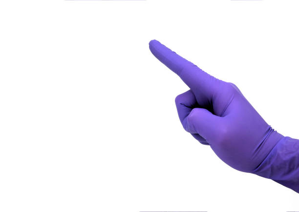 Hand in purple glove pointing the index finger. Medical personal pointing on something important. stock photo