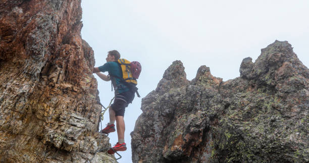 istock Young man climbs via ferrata ridge in the mist 1208898688