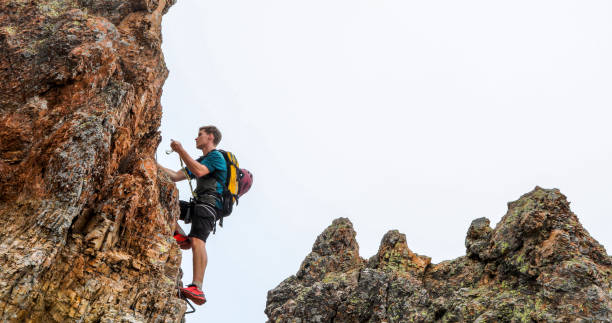 young man climbs via ferrata ridge in the mist - climbing rock climbing rock mountain climbing imagens e fotografias de stock