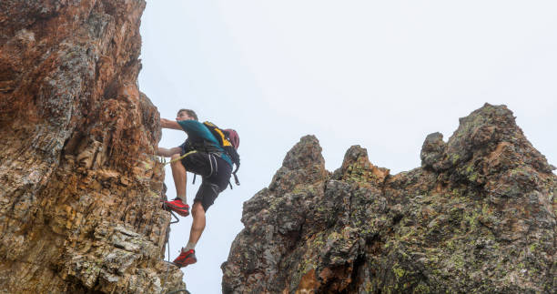 istock Young man climbs via ferrata ridge in the mist 1208898700