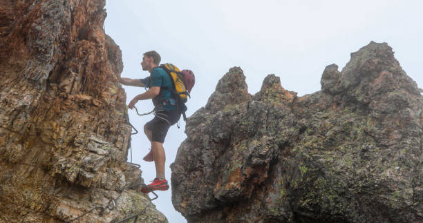 istock Young man climbs via ferrata ridge in the mist 1208898704