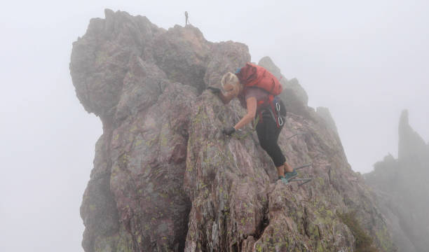 mujer madura se mueve a lo largo de la cresta rocosa en una vía ferrata en la niebla - 11207 fotografías e imágenes de stock