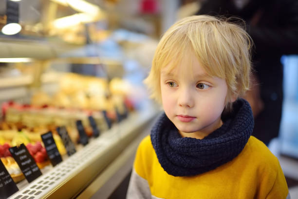 маленький мальчик любуясь торты и другие сладости на витрине в кафе или супермаркете - overweight child little boys diabetes стоковые фото и изображения