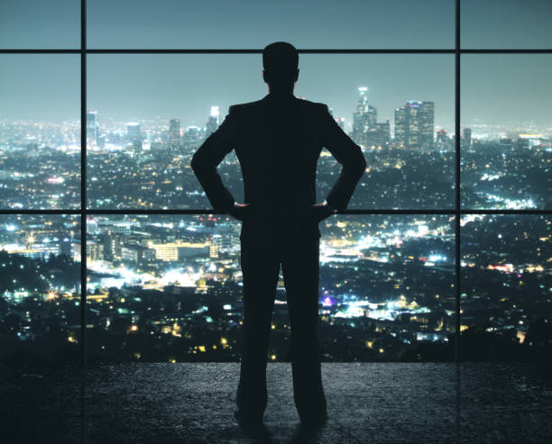 istock Businessman standing in night office 1208904230