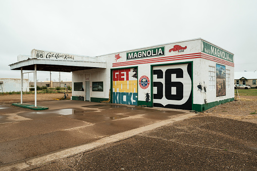 Tucumcari, New Mexico USA - October 4, 2019: Cityscape view of a vintage and closed Americana style Magnolia gasoline station with colorful signage along the historic Route Highway 66 that runs through this small rural town located in Quay County in northeast New Mexico.
