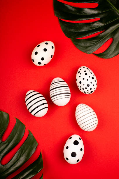 istock Creative graphic eggs with green tropical leaves on bright red background. 1208906084