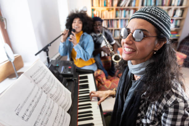 istock Woman with sunglasses playing the piano, with a group 1208909149
