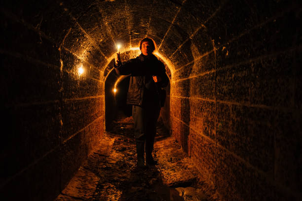 istock Urban explorer with candle in old vaulted underground tunnel 1208911743