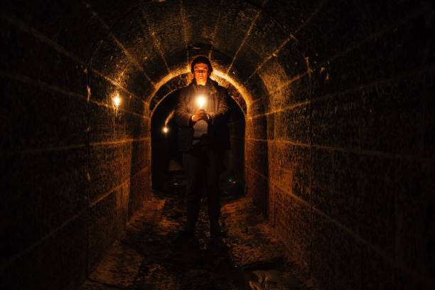istock Urban explorer with candle in old vaulted underground tunnel 1208911896