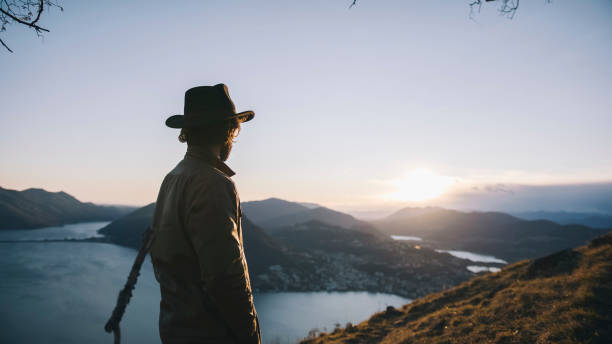 istock Man pauses at edge of trail, mountainside 1208913762