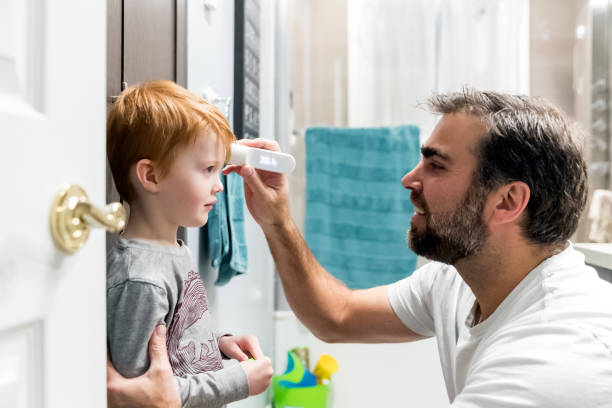 istock Father measuring temperature of his sick boy with infrared thermometer 1208922687