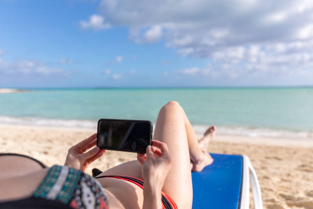 istock Woman Relaxing at Beach and Looking at Mobile Phone 1208923464