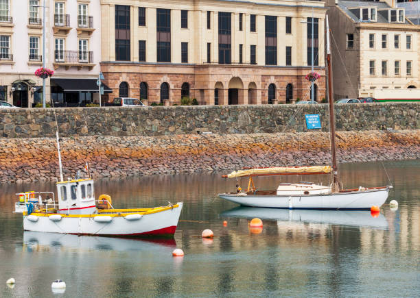 Fishing and Sail boats moored along the sea wall at Saint Peter Port in Guernsey Fishing and Sail boats moored along the sea wall at Saint Peter Port in Guernsey guernsey city stock pictures, royalty-free photos & images