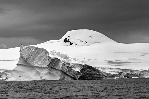 Black and White Iceberg Glaciers Mountains Charlotte Bay Antarctic Peninsula Antarctica.  Glacier ice blue because air squeezed out of snow.