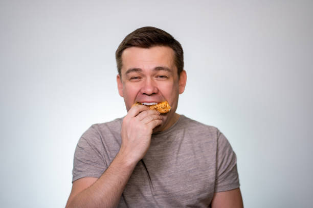 istock man puts slice of pizza in his mouth completely 1208951036
