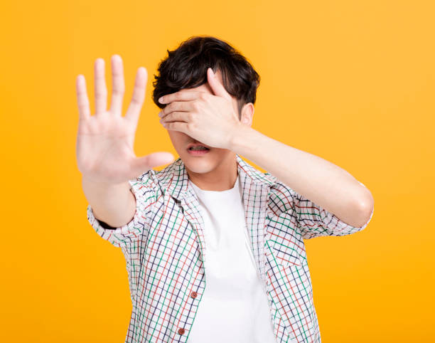 istock scared young man hand cover eyes with stop sign 1208954543