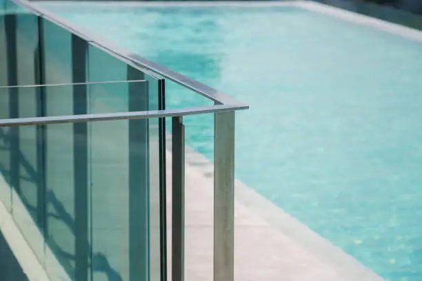 closeup modern flat stainless railing and glass wall on outdoor poolside.