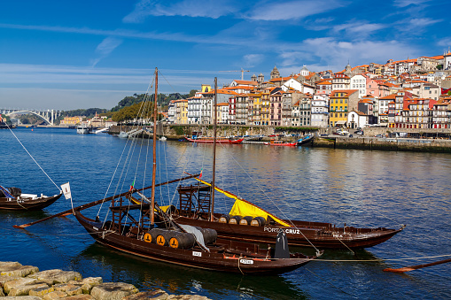 Porto, Portugal - 04 October 2016: Boats carrying barrels of porto wine seen docking at river bank on background cityscape.