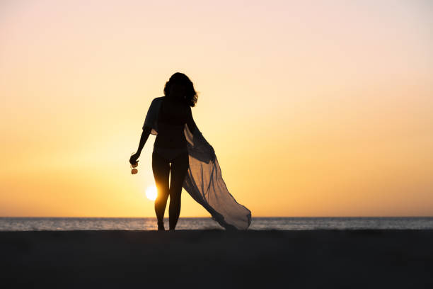 (Selective focus) Stunning view of the silhouette of a girl walking on a beach during a beautiful and romantic sunset. White Beach, Boracay Island, Philippines. (Selective focus) Stunning view of the silhouette of a girl walking on a beach during a beautiful and romantic sunset. White Beach, Siargao Island, Philippines. summer fashion philippines palawan stock pictures, royalty-free photos & images