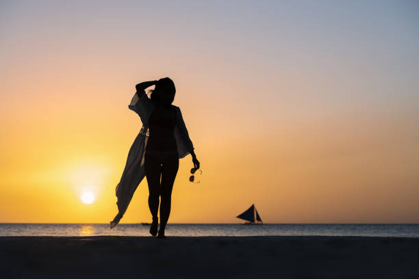 (orientation sélective) vue imprenable de la silhouette d’une fille marchant sur une plage pendant un coucher de soleil beau et romantique. white beach, boracay island, philippines. - people traveling elegance philippines palawan photos et images de collection